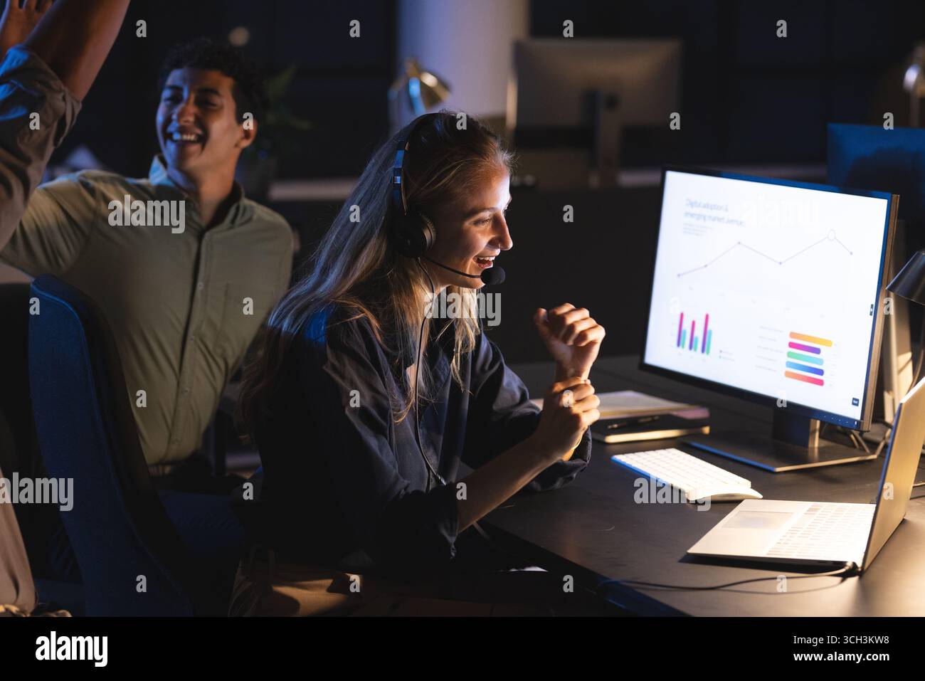 Businesswoman wearing headset analyzing data on computer at night office Stock Photo