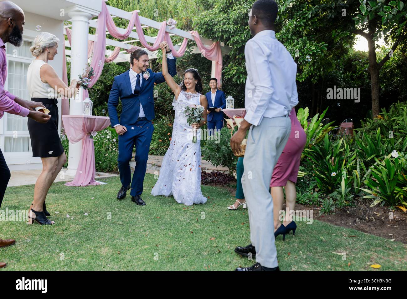 Bride and groom joyfully dancing outdoors with guests celebrating around them Stock Photo