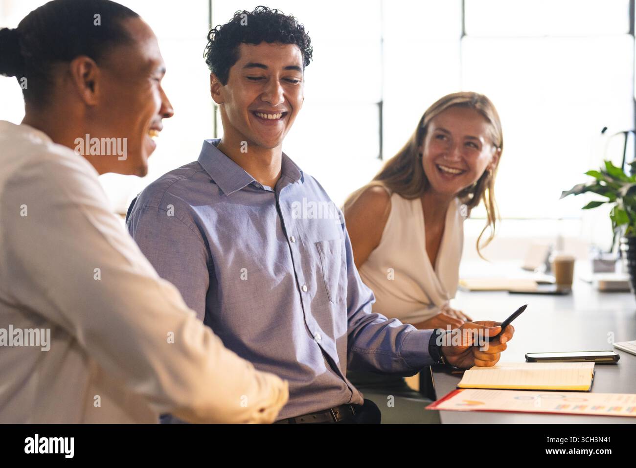 Colleagues in office discussing project, smiling and collaborating with documents Stock Photo