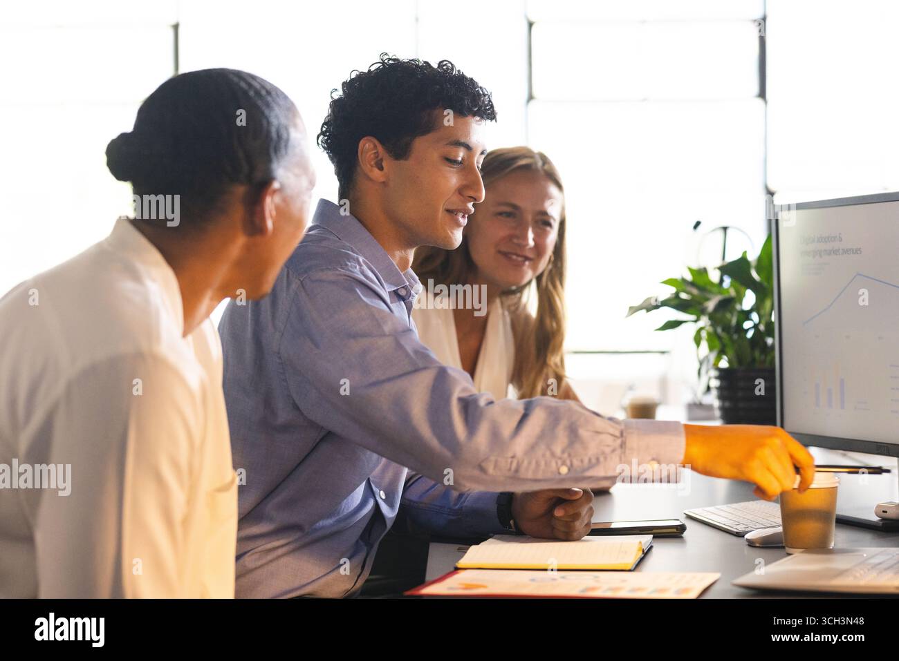 Business team collaborating on project, analyzing data on computer in modern office Stock Photo