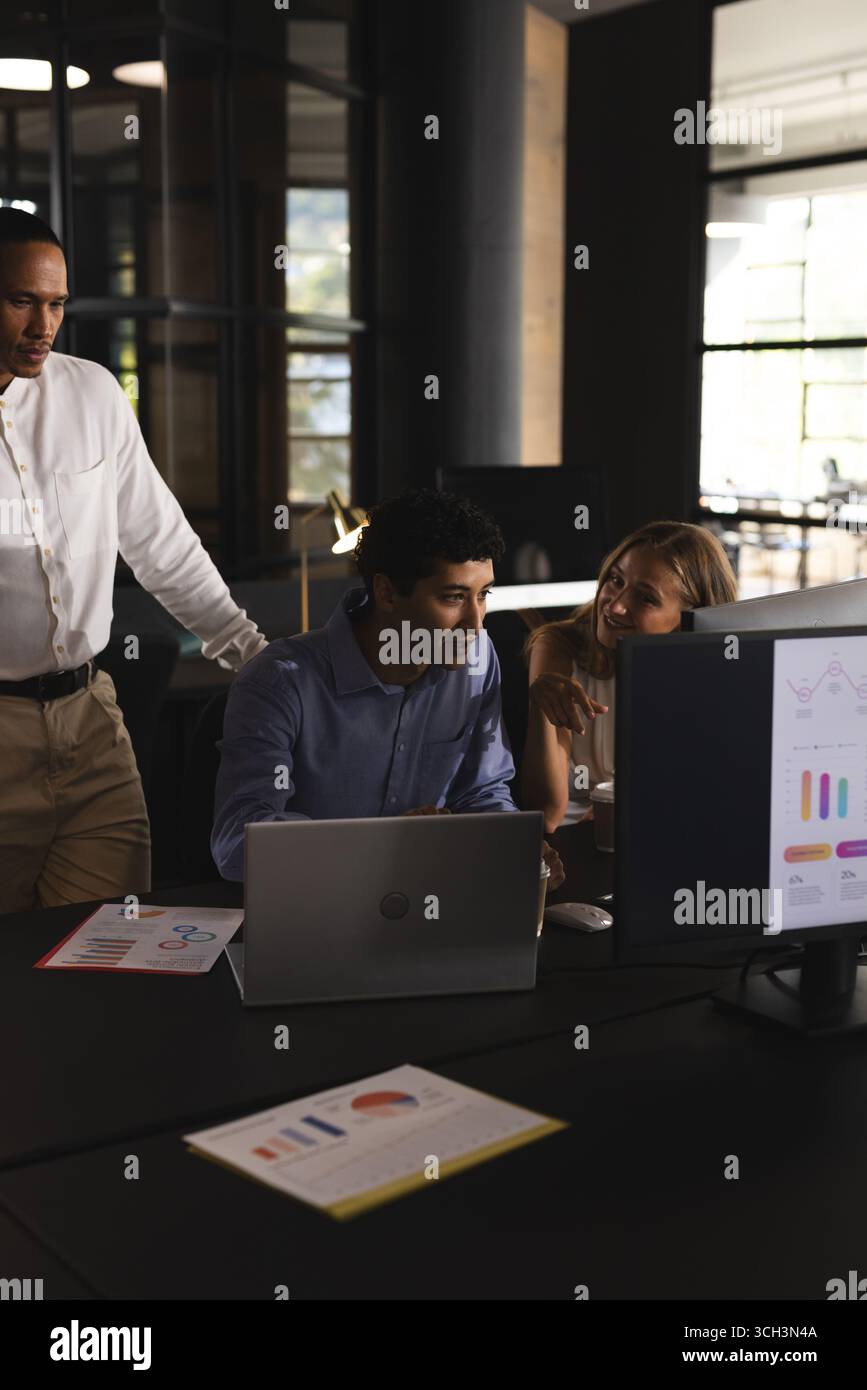Collaborating on project, business professionals using laptop and charts in office Stock Photo