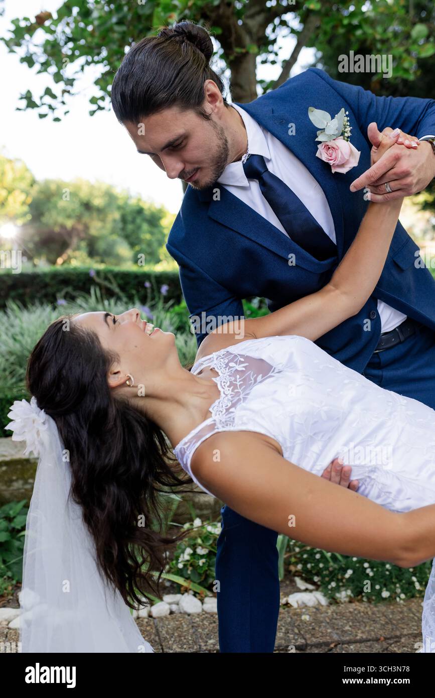 Bride and groom dancing joyfully outdoors, sharing romantic moment together Stock Photo