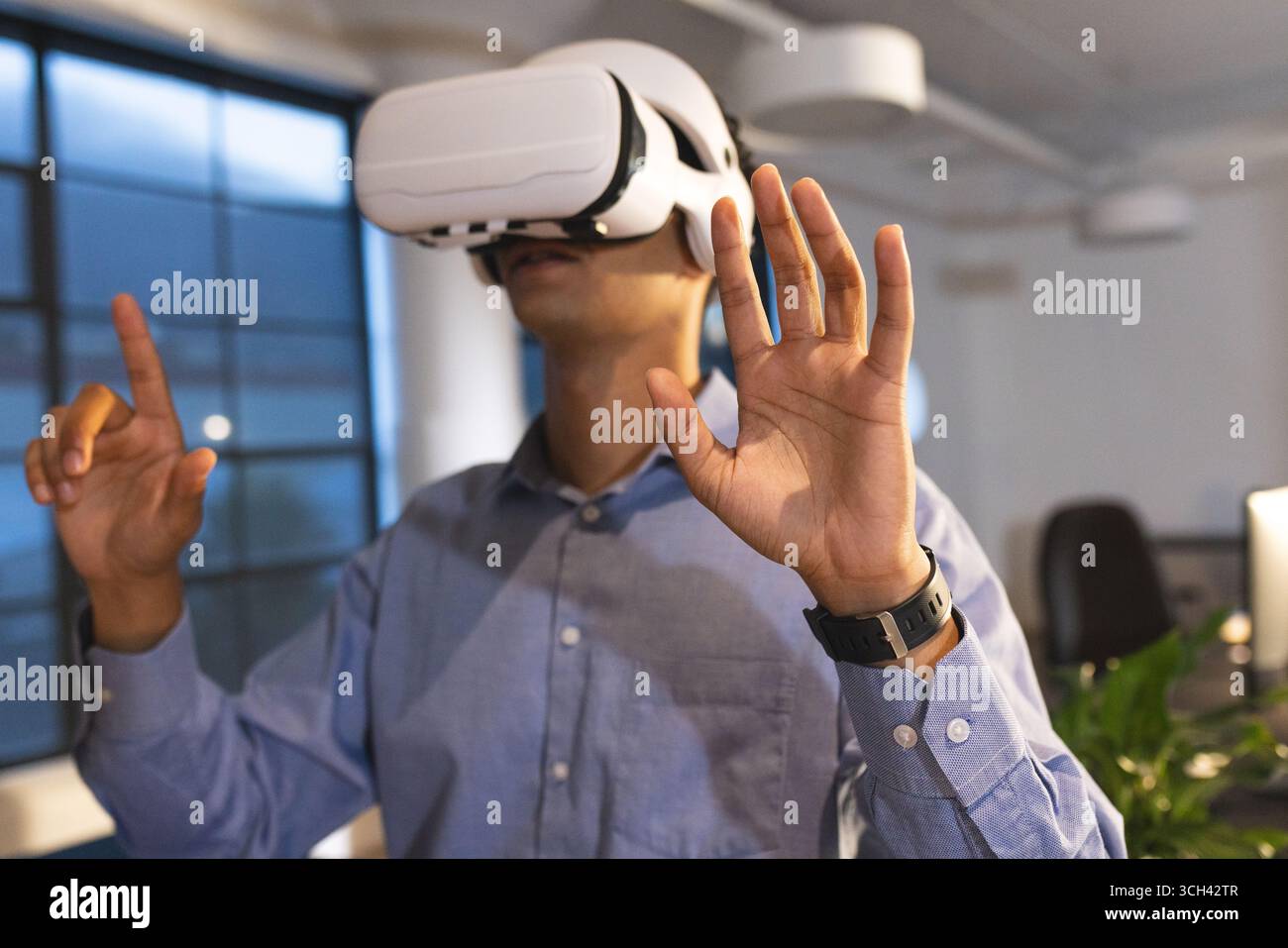Businessman using VR headset in modern office, interacting with virtual environment Stock Photo
