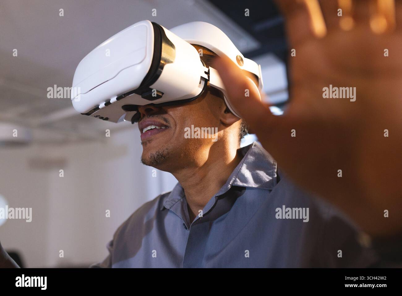 Using VR headset, African American man exploring virtual reality in office setting Stock Photo
