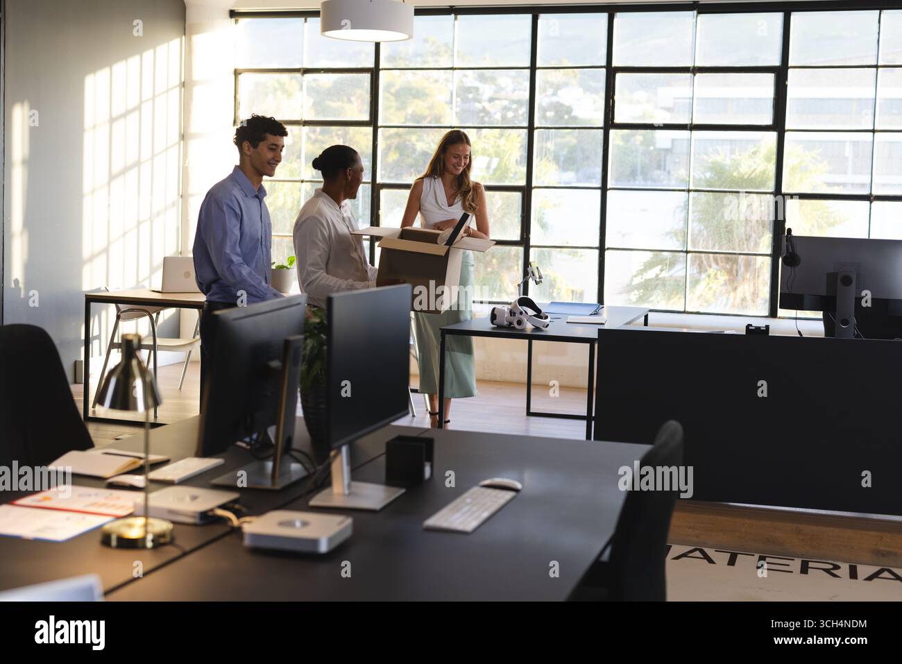 Colleagues in modern office discussing project while holding documents and smiling Stock Photo