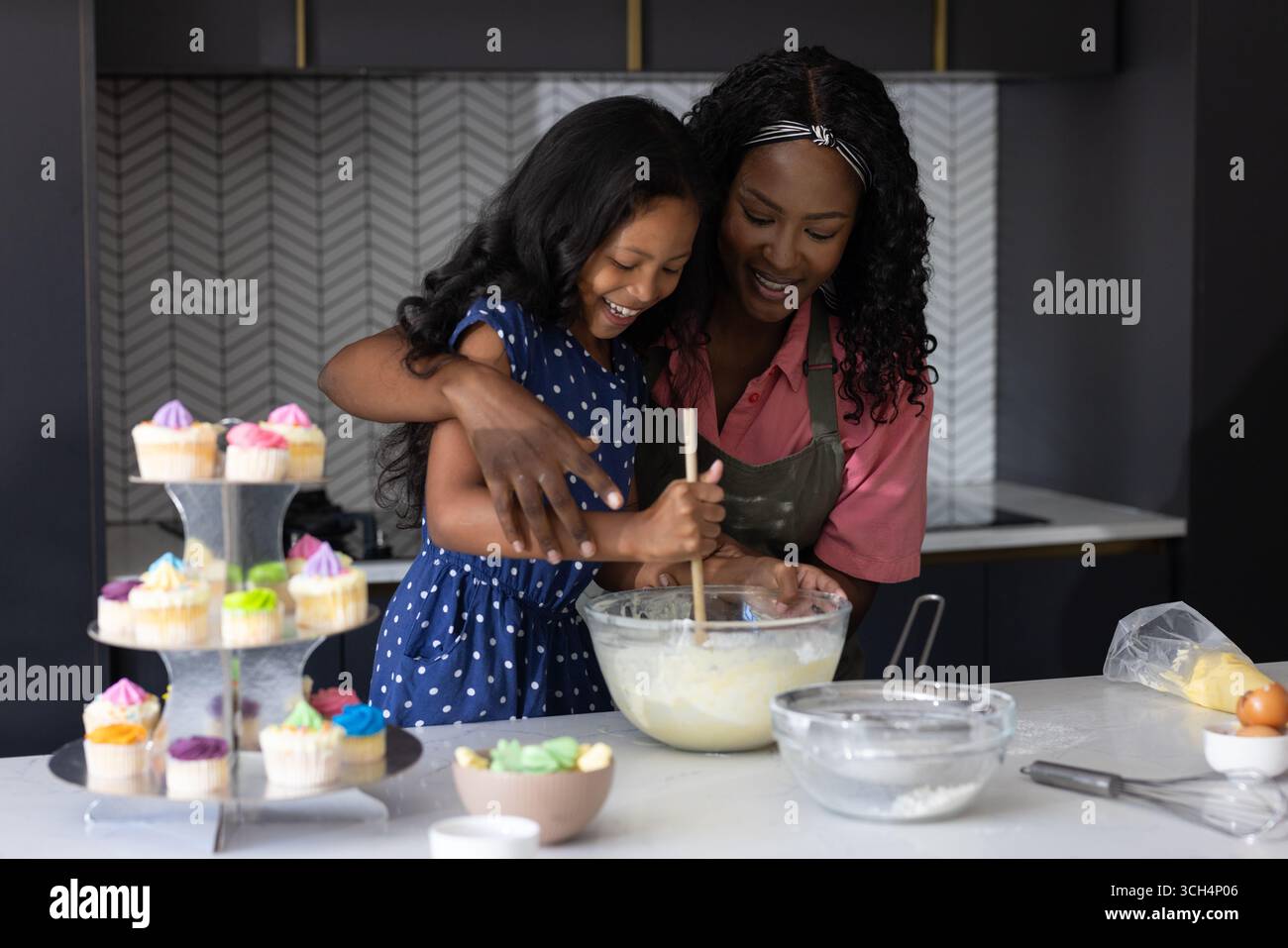 Baking cupcakes, mother and child sharing joyful moment in modern kitchen together Stock Photo
