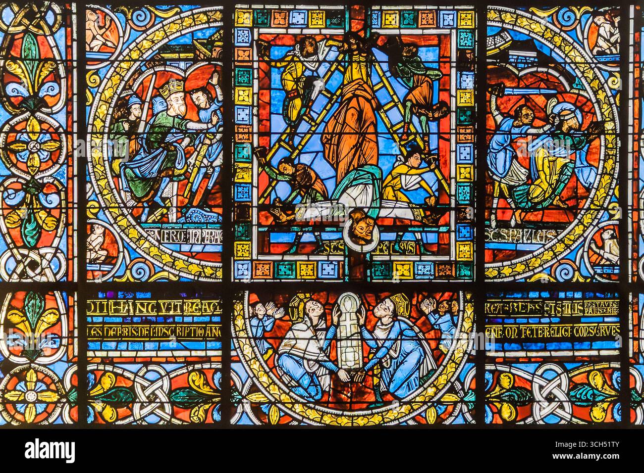 A detail from the famous stained glass window in the apse of Saint-Pierre Cathedral (Cathédrale Saint-Pierre de Poitiers) shows the martyrdom of the apostles Peter and Paul, Rue Emile Faguet, Poitiers, Nouvelle-Aquitaine, France. In the centre Peter hangs upside down on the cross, on the right an executioner beheads Paul, and on the left Emperor Nero condemns the apostles. The inscriptions "SCS PETRUS" and "SCS PAULUS" name the two saints. Eleanor of Aquitaine and Henry II Plantagenêt donated the window. At the time they were Queen and King of England and Dukes of Normandy and Aquitaine. The l Stock Photo