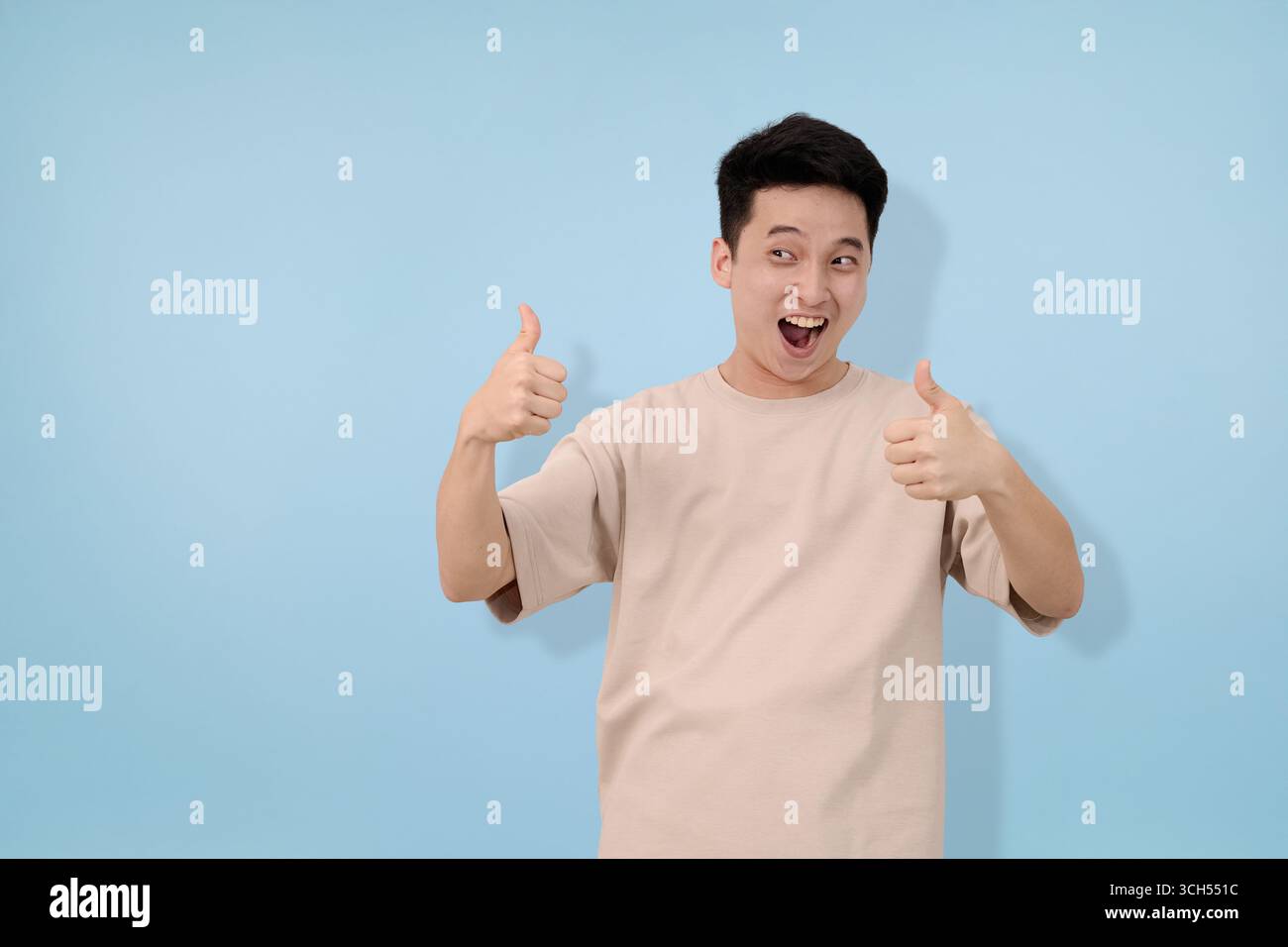 young man making thumbs up gesture in studio background Stock Photo