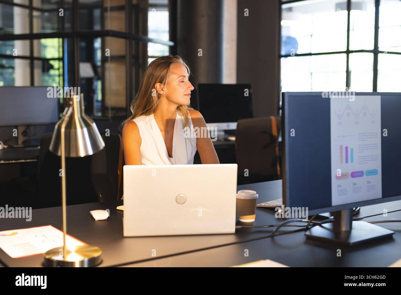 Analyzing data on computer screen, businesswoman working late in office, looking thoughtful Stock Photo
