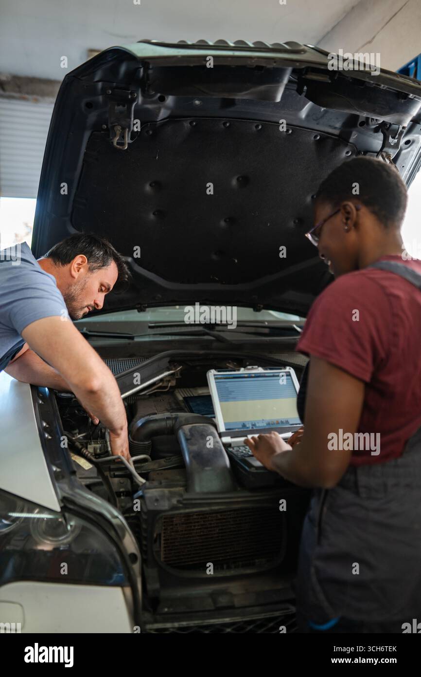 Mechanics repairing car engine using laptop in auto repair shop Stock ...
