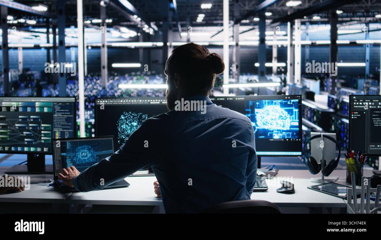 Server room software developer using AI to review infrastructure diagnostics. IT employee in data center analyzing performance data using artificial intelligence technology on devices, camera A Stock Photo