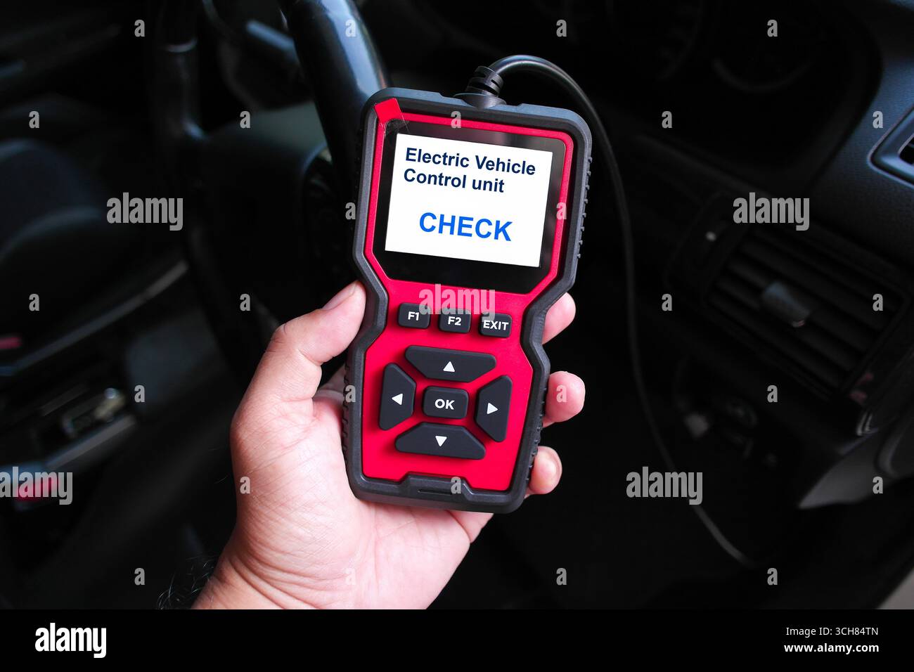 Hand holding an OBD2 scanner device for electric vehicle diagnostics ...