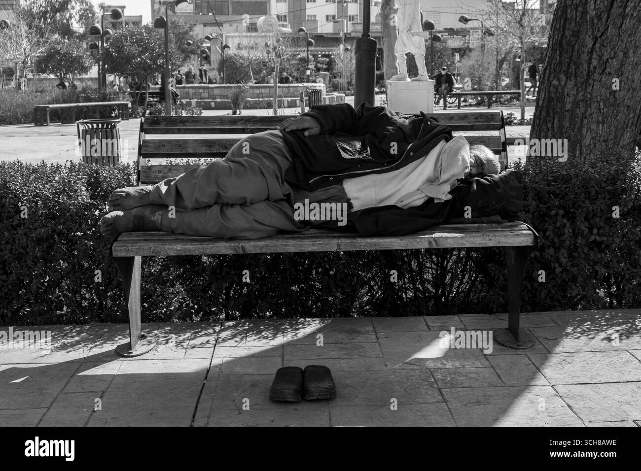 A Kurdish man lies on a street in Ranya, exhausted and alone. His body language shows poverty, despair, and emotional struggle. The quiet street empha Stock Photo