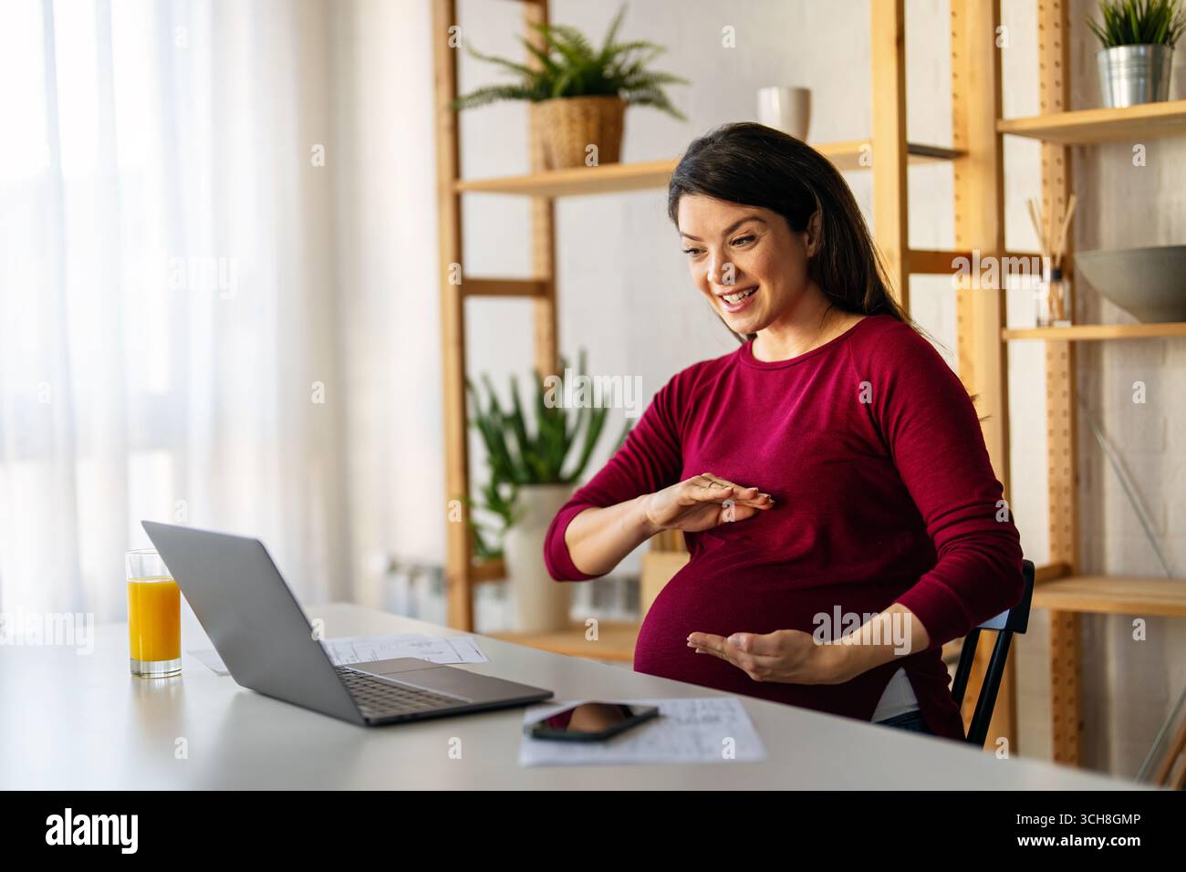 Young pregnant business woman, online teacher looking at laptop, online remote video call concept Stock Photo