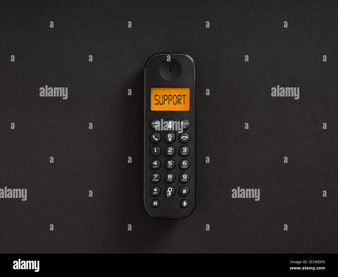 Black wireless telephone showing support message on display on a black background, concept of customer service Stock Photo