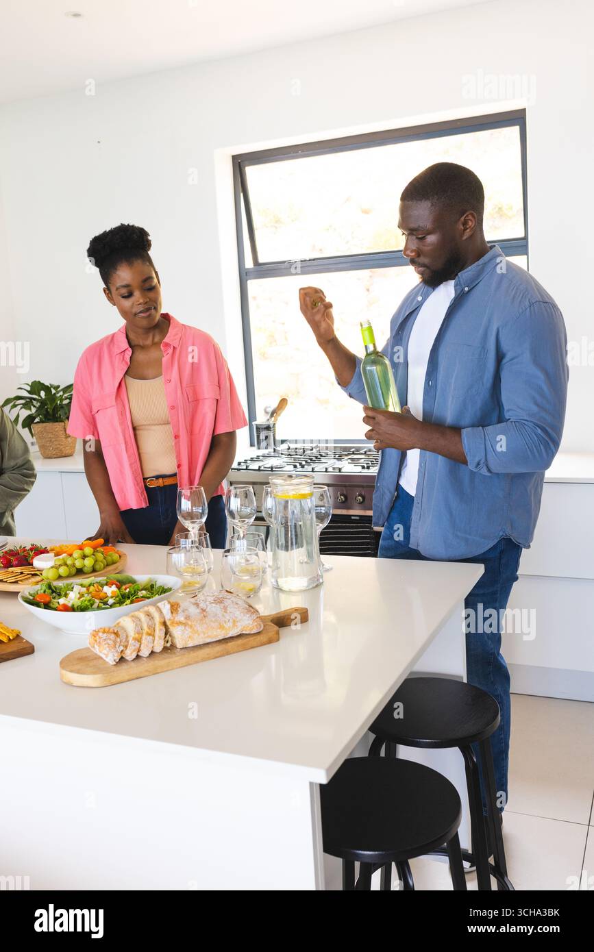 Friends enjoying wine and conversation in modern kitchen during casual gathering. socializing, lifestyle, dining, beverage, leisure, celebration Stock Photo