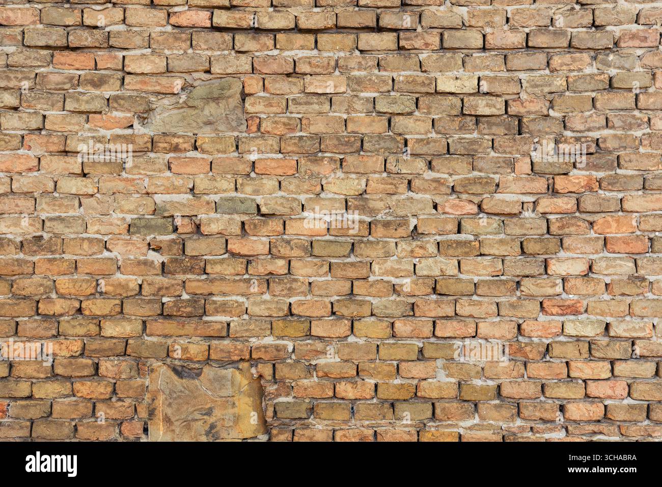 Weathered brick wall surface with irregular patterns and aged textures, perfect for backgrounds or architectural design Stock Photo