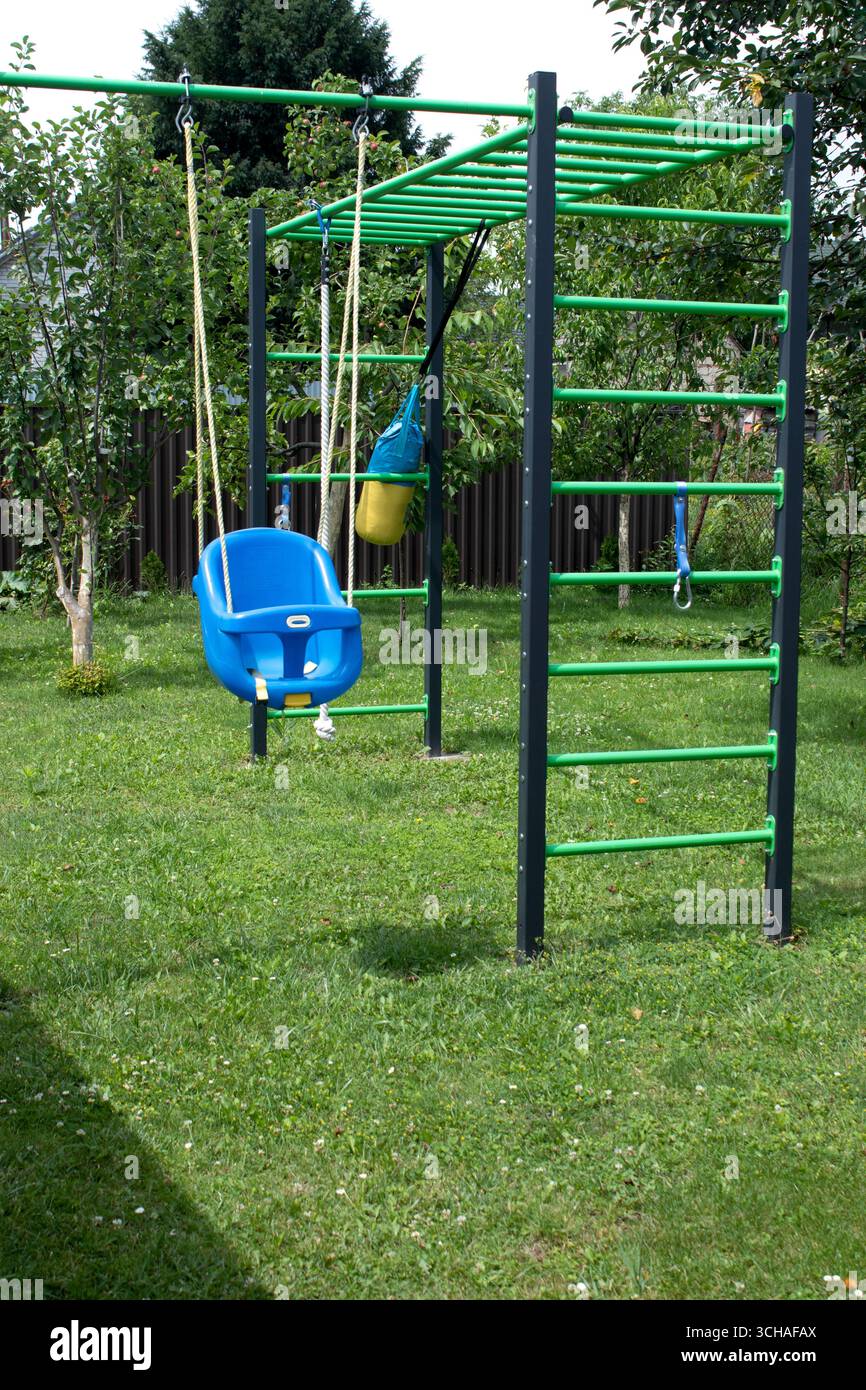 Blue plastic swing in green sunny garden, front view Stock Photo