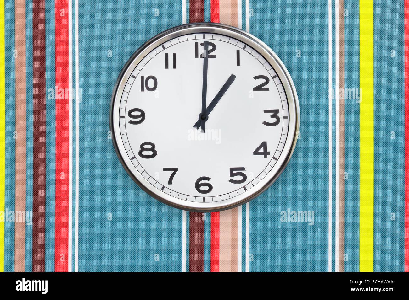 Office clock showing one o'clock on a colorful wall Stock Photo