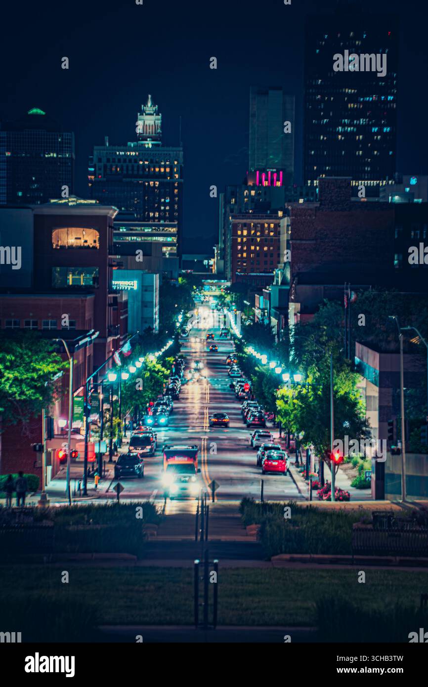 A vibrant city street illuminated at night with cars, streetlights, and ...