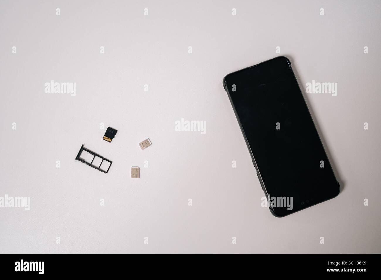 Sim cards and memory card positioned near sleek smartphone on white surface, representing mobile technology connectivity and potential device Stock Photo