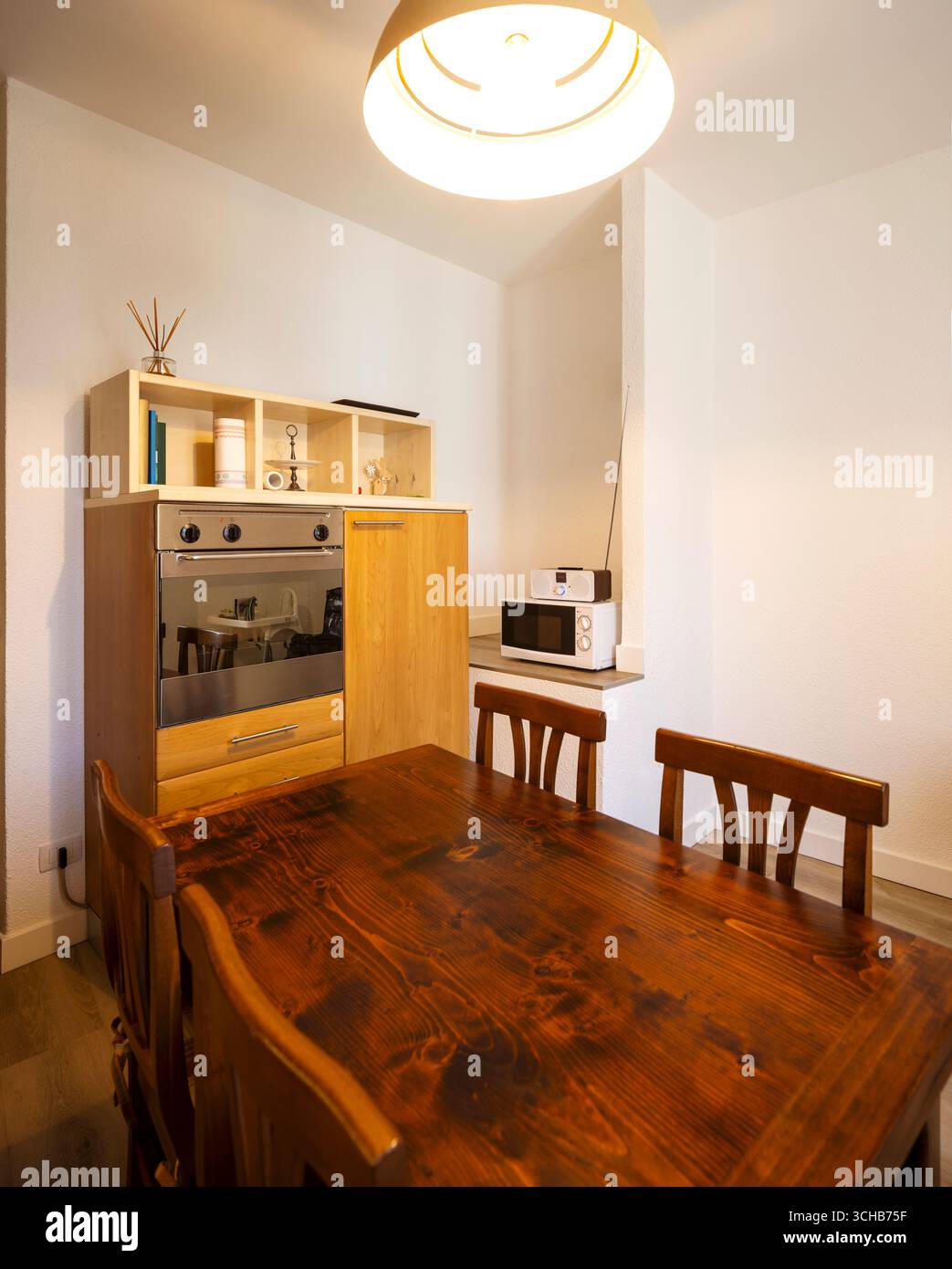 Interior of a kitchen with lots of wood in an old Italian style. In the foreground is the table and chairs. No one inside. Stock Photo