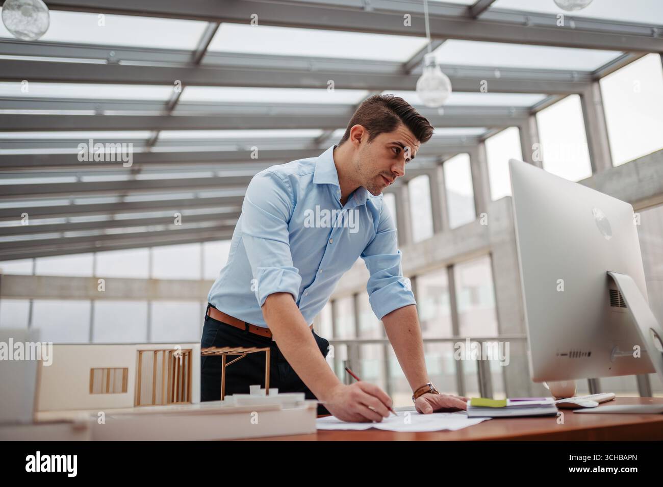 Young businessman, engineer working in office, working on plan or technical document. Stock Photo