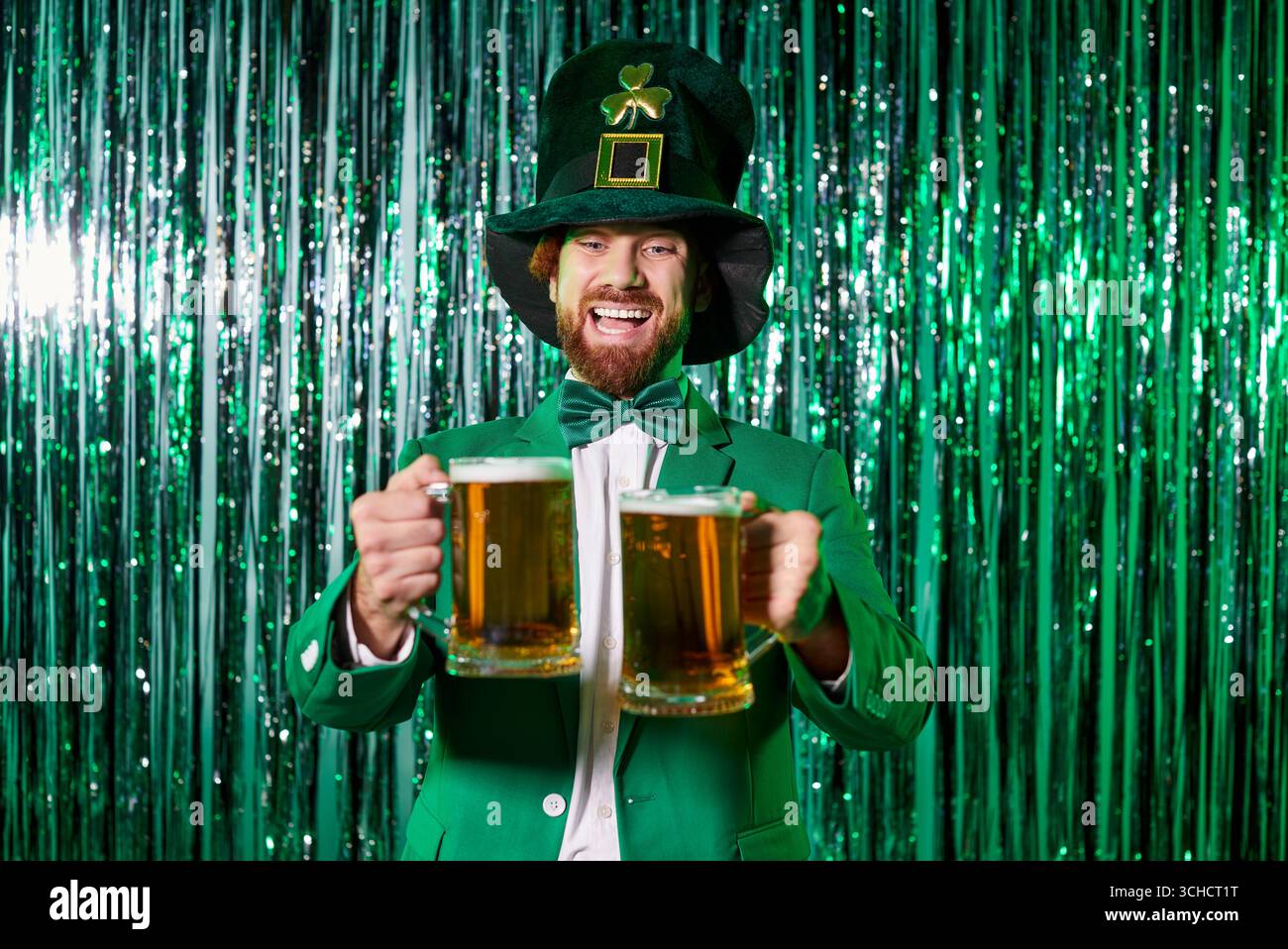 Ginger young man dressed as leprechaun holding two beer mugs Stock Photo