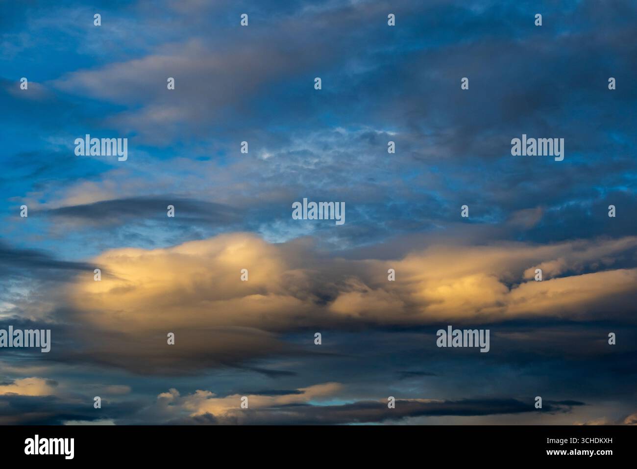 Golden clouds against a deep blue evening sky Stock Photo