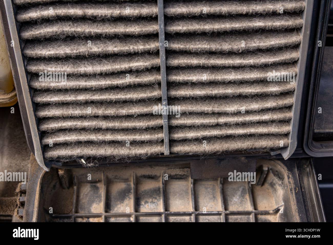 A person removing a very dirty engine air filter from the car's intake ...