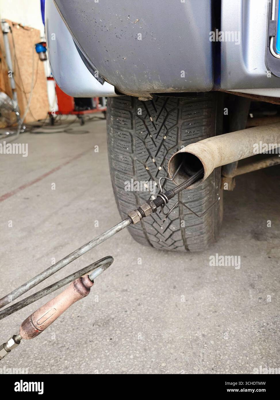 Exhaust gas analyser probe inside car's tail pipe during technical inspection process. Close up, low angle shot, no people Stock Photo