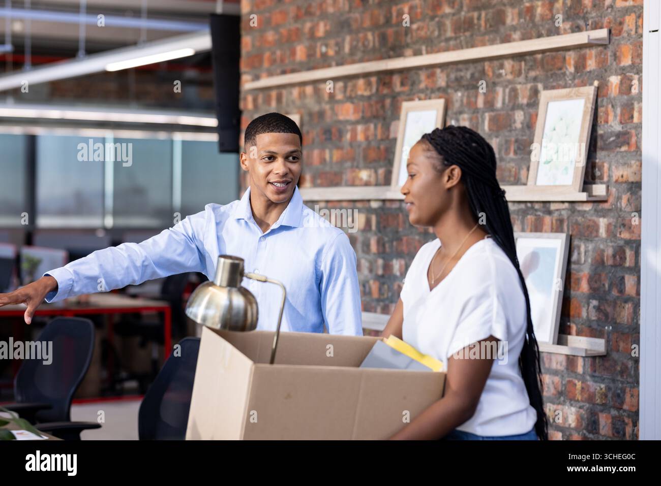 Diverse colleagues in office discussing while unpacking box, collaborating on project Stock Photo