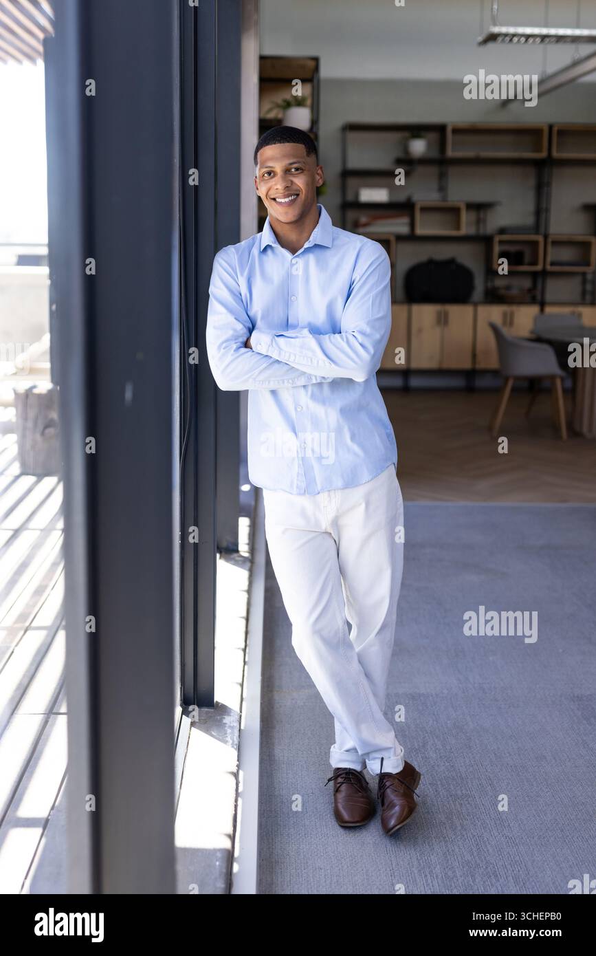 Confident man in office wearing semi-formal attire, smiling by large window, copy space Stock Photo