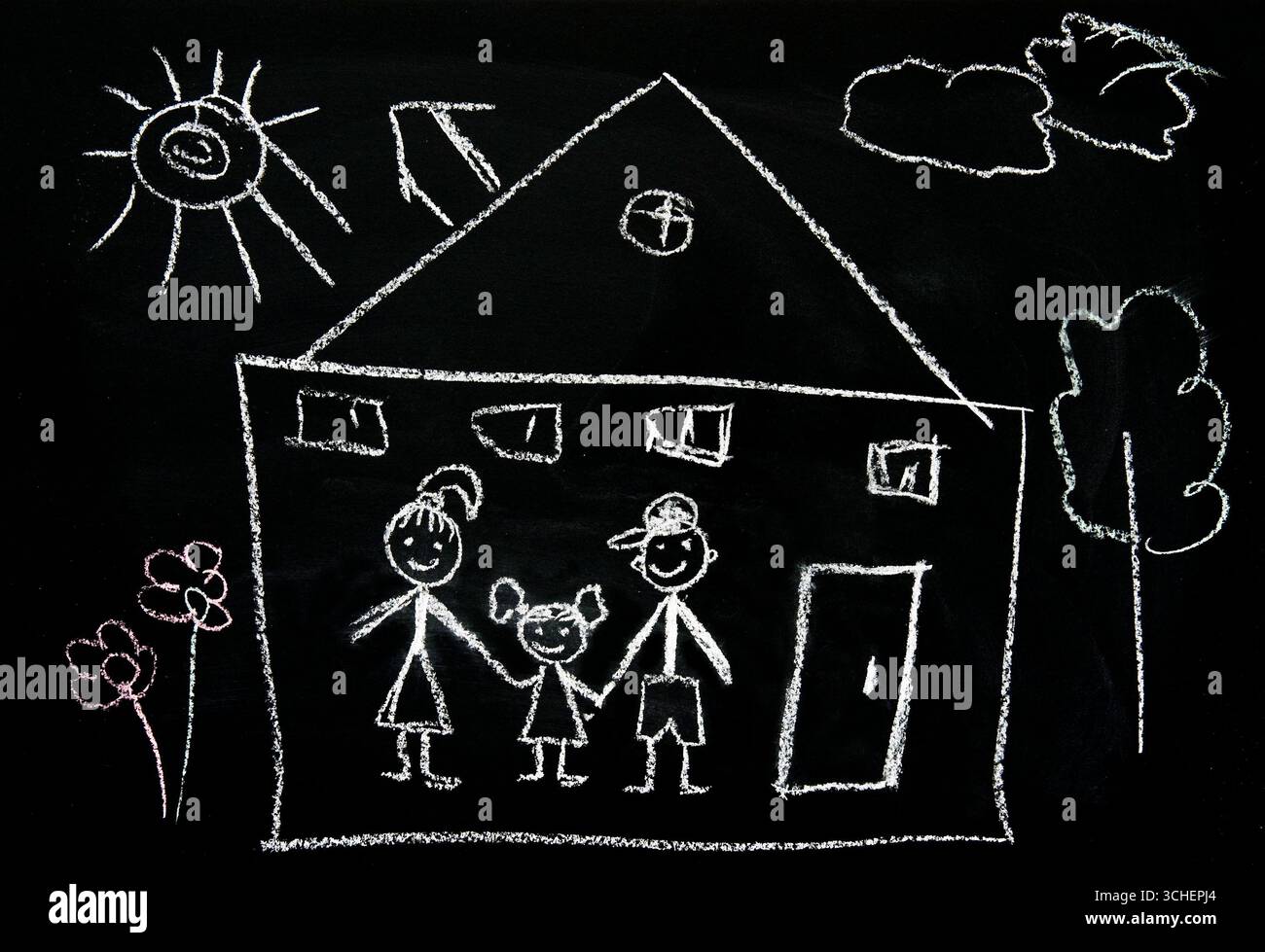 on a blackboard a house family tree and bright sun are drawn with chalk. Stock Photo