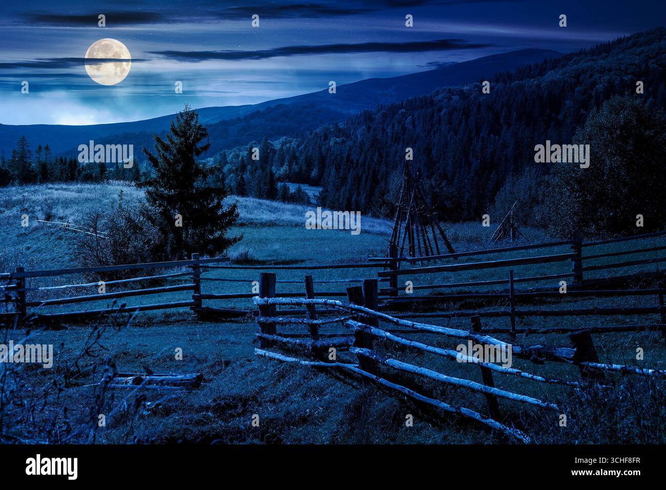 mountainous rural landscape in autumn at night. wooden fence near the path through grassy meadow on the hillside. scenery with fir forest on the mount Stock Photo