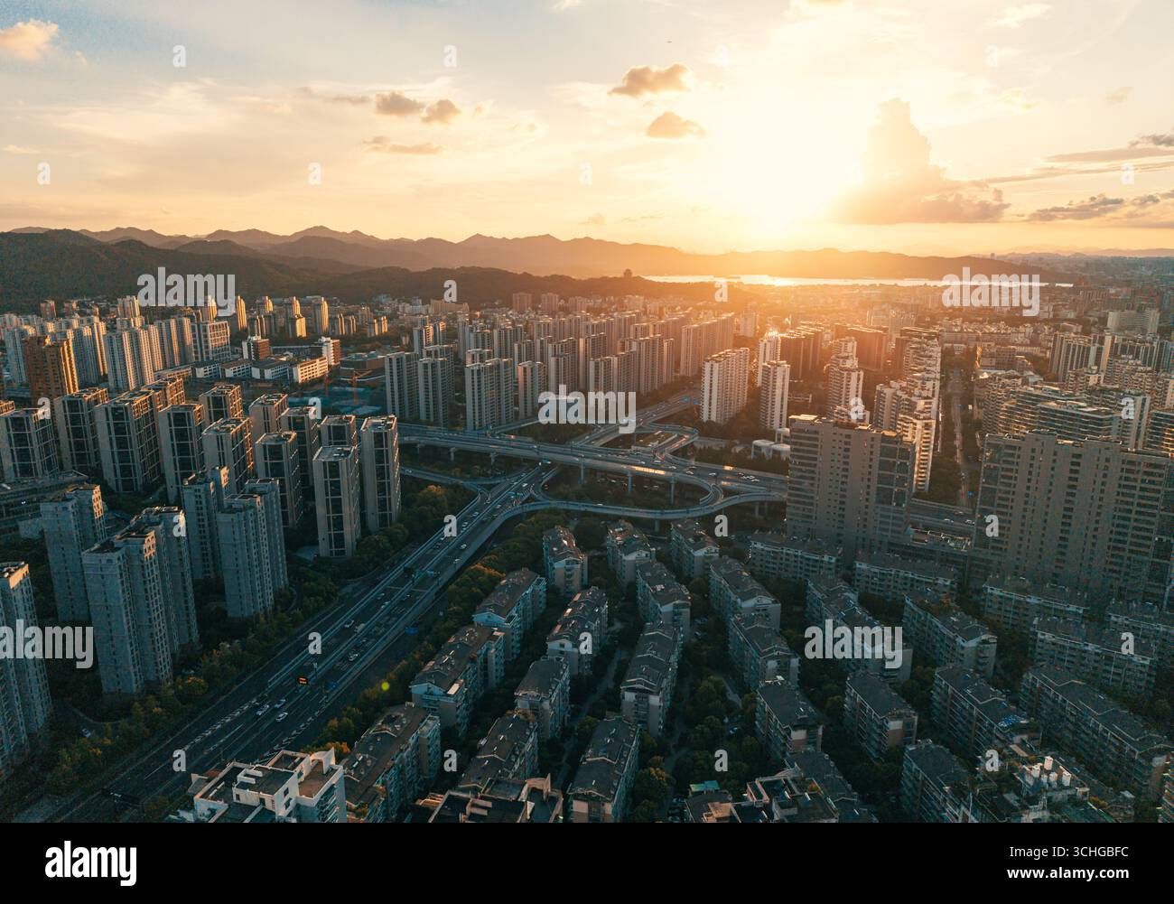 Aerial view of a residential buildings alongside a multilane highway interchange filled with moving vehicles Stock Photo
