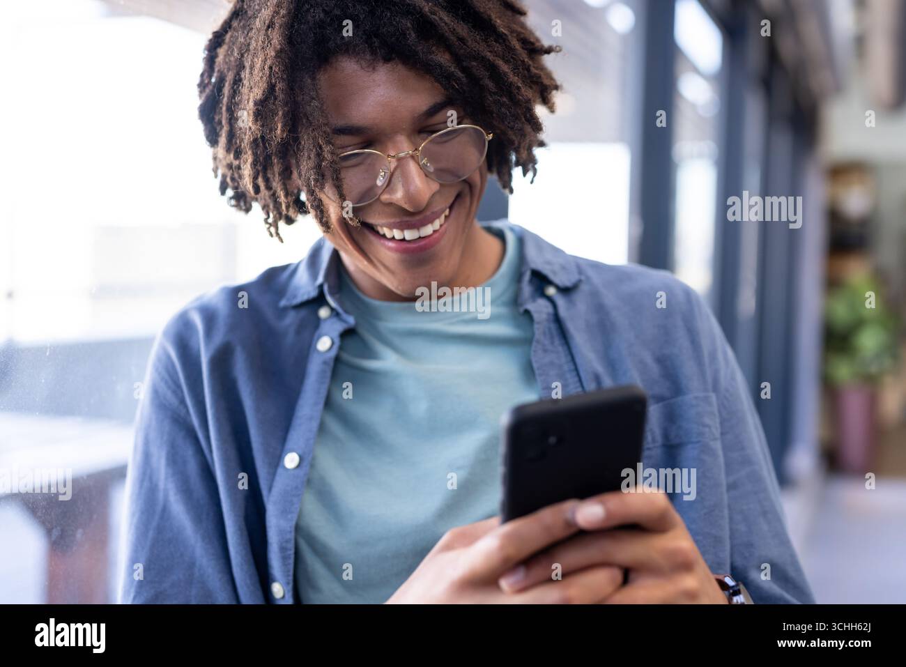 In office, man using smartphone, reading positive message and smiling Stock Photo