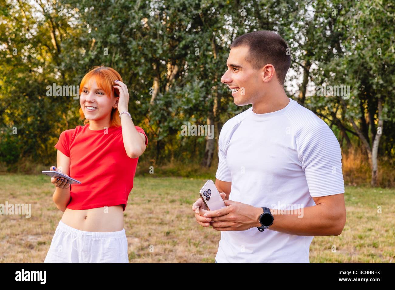 Young couple using smartphones while walking in park Stock Photo