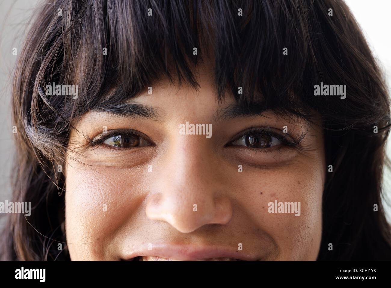 Smiling woman with dark hair looking directly at camera, showing happiness, at home Stock Photo