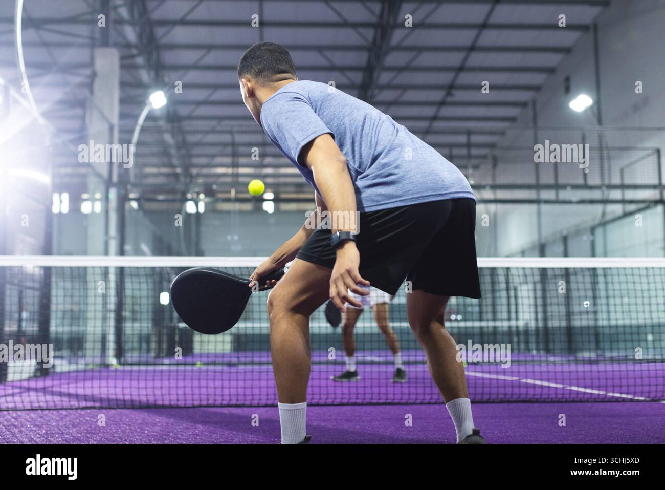 Male opponents positioning on padel court near net with black rackets ...