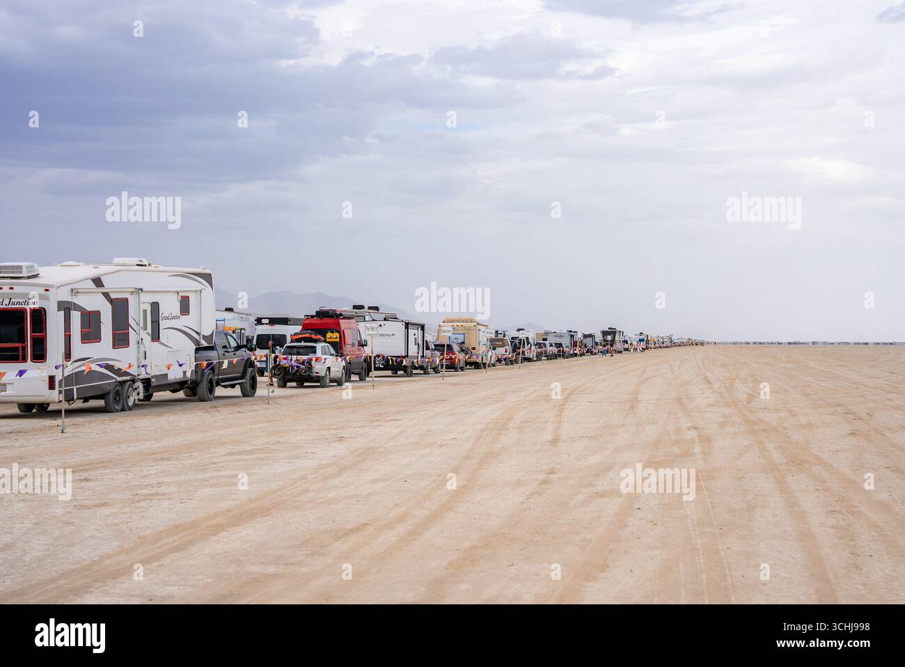 A long line of RVs, trailers, and vehicles stretches across a flat ...