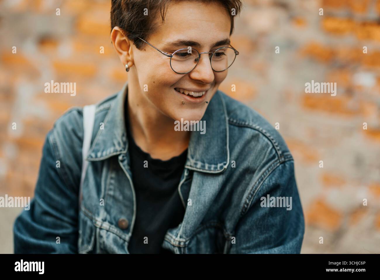 Smiling young man with piercing looking down Stock Photo