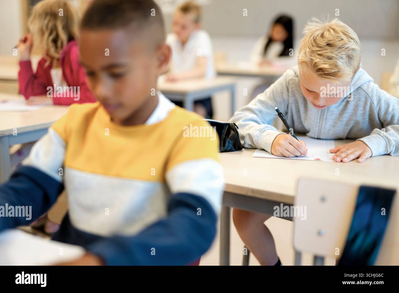Group of elementary students writing in paper during exam at school Stock Photo