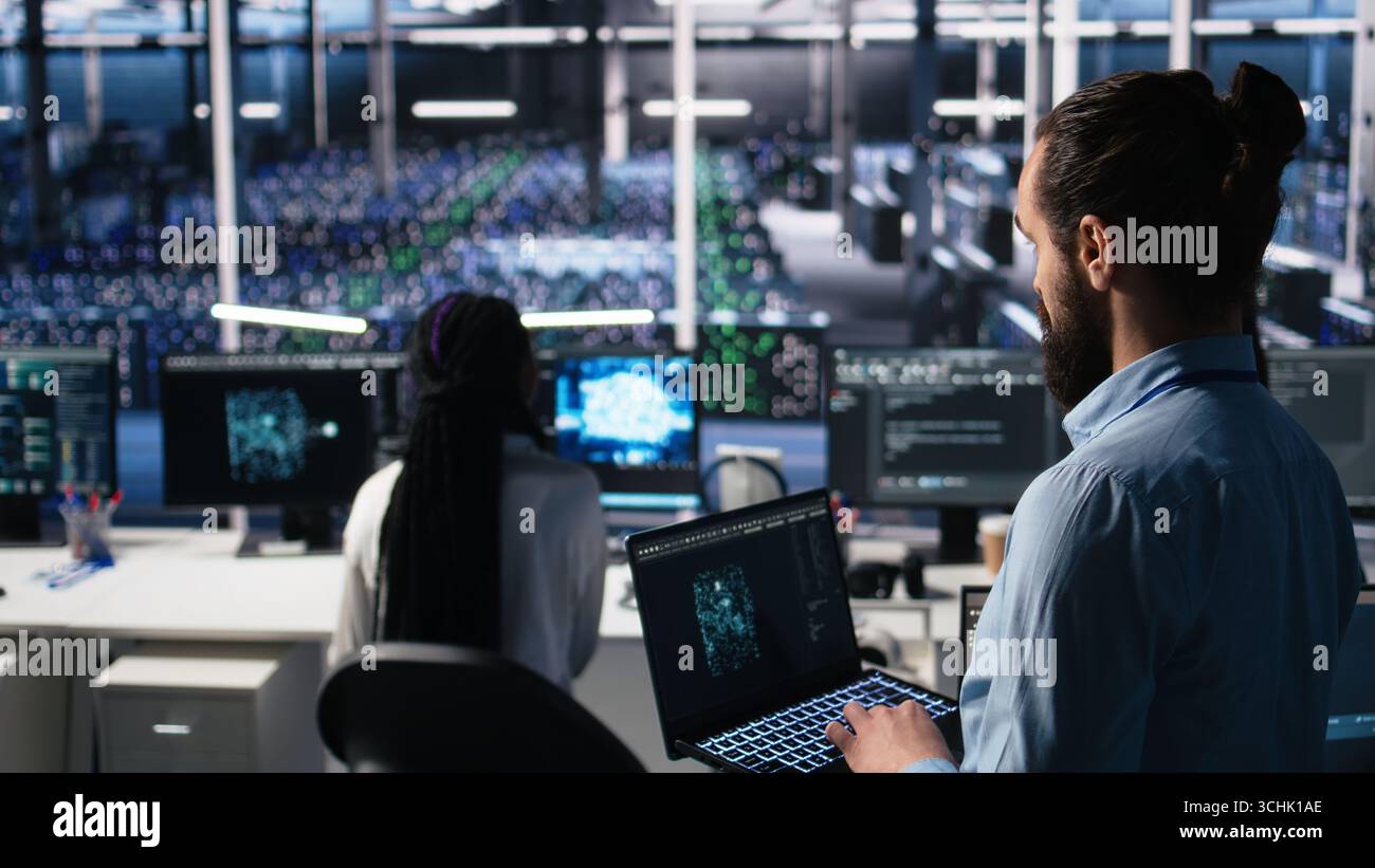 Server room technician using AI LLM chatbot to review infrastructure diagnostics. IT expert in data center using artificial intelligence large language model to analyze performance data, camera A Stock Photo