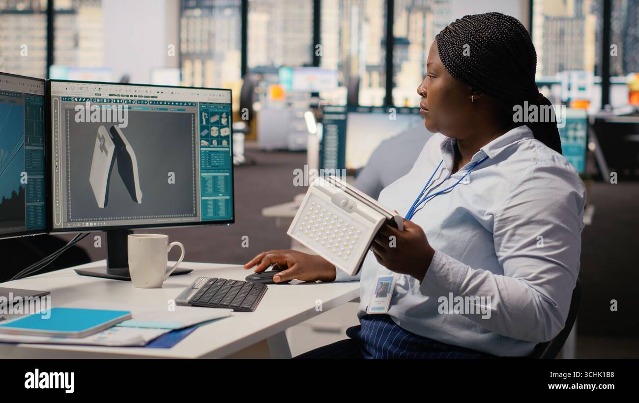 Product developer in office using advanced solar cell technology to create renewable energy based device. RD professional tests solar panel lamp prototype to maximize power output, camera B Stock Photo