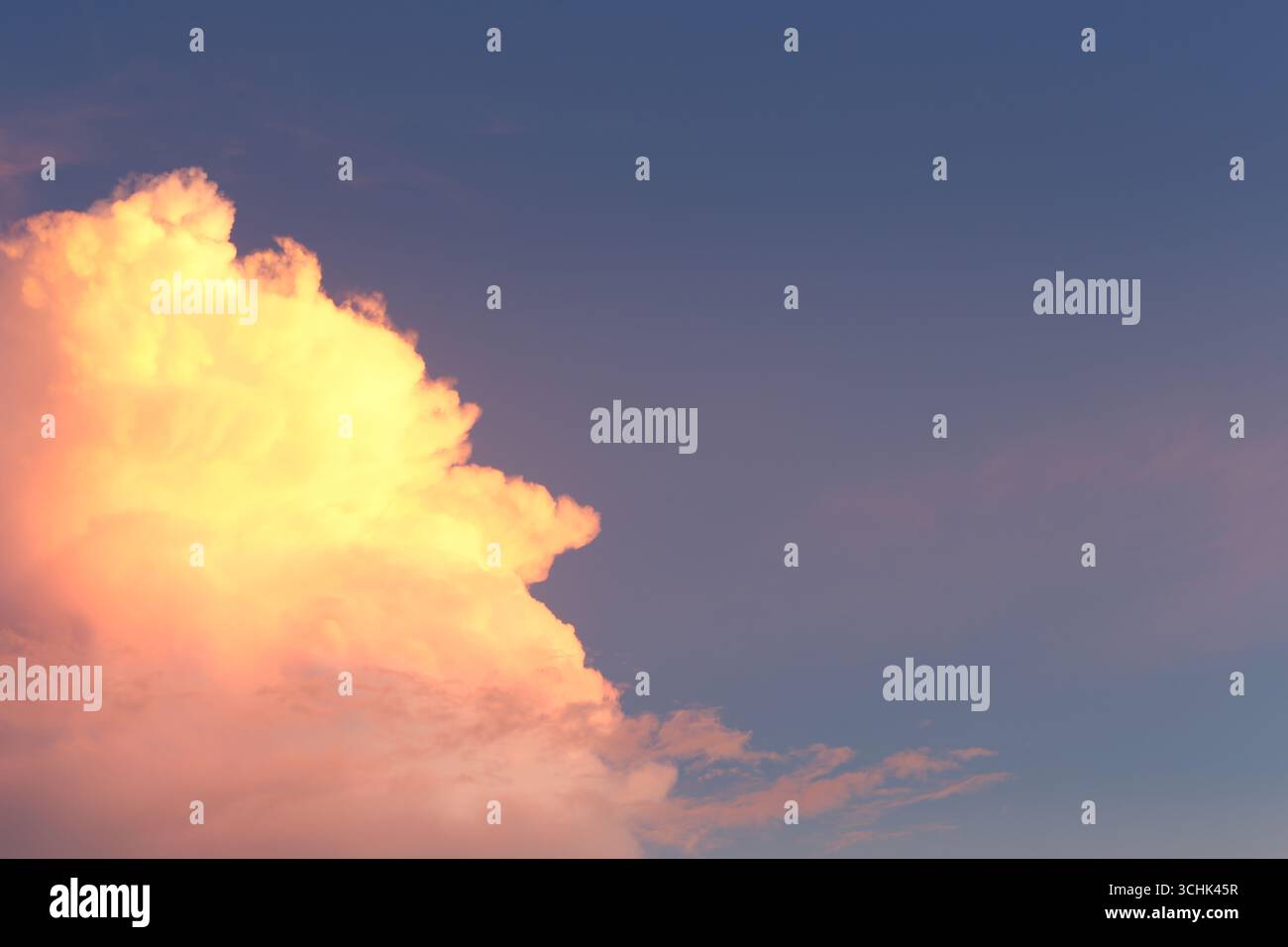 A stunning view of the sky during sunset with fluffy clouds painted in warm colors, offering a serene and tranquil atmosphere perfect for relaxation a Stock Photo