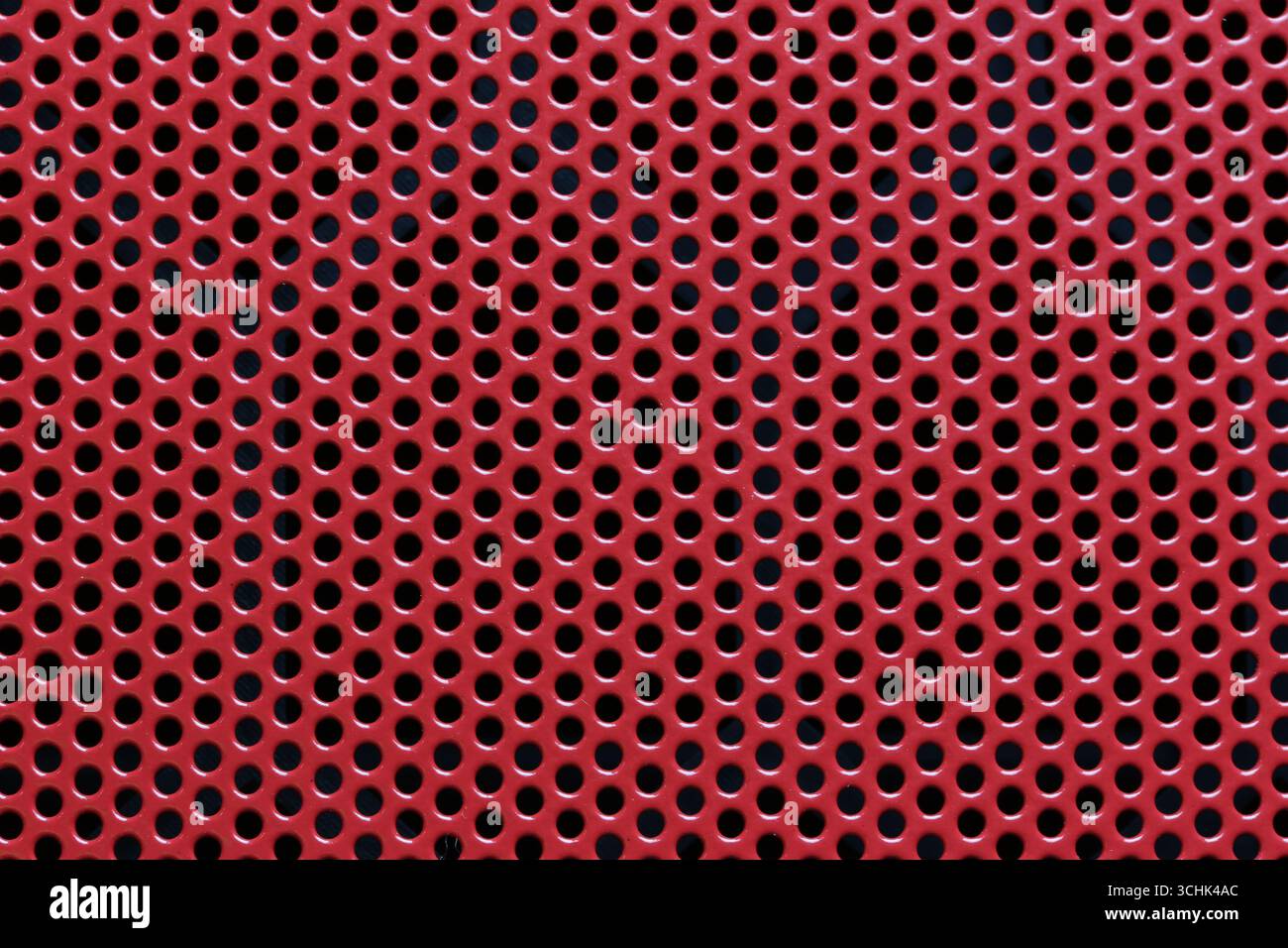 A bright red perforated metal sheet featuring uniform holes, perfect ...