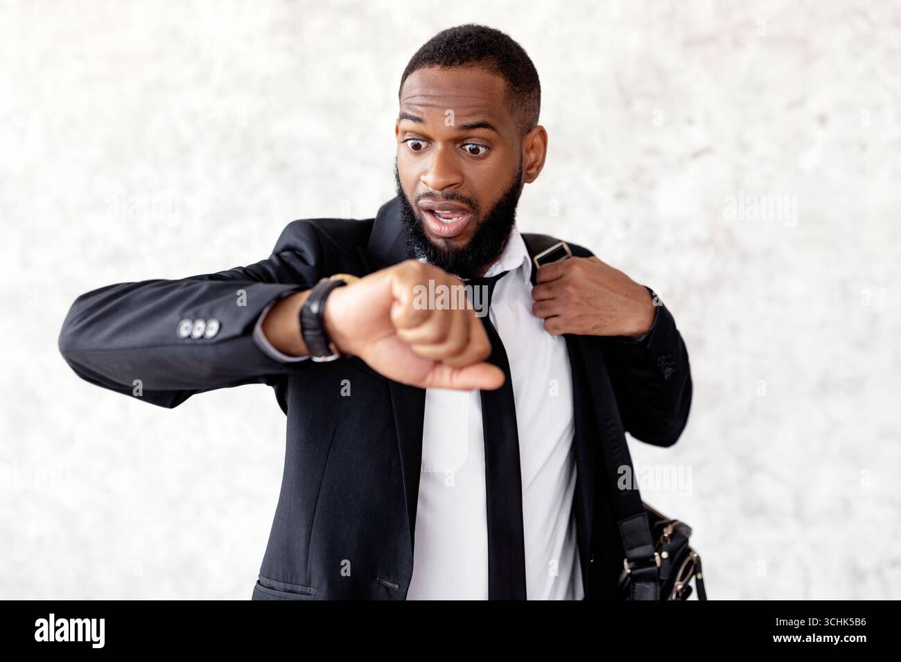 Scared black man is late for work looking at watch Stock Photo