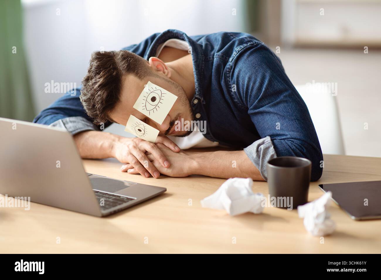 Exhausted arab guy with eyes drawing sleeping at workdesk Stock Photo