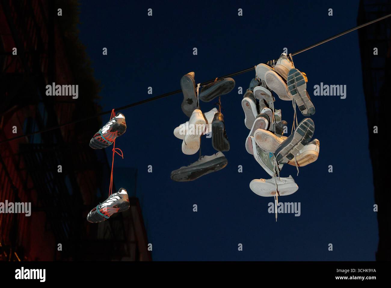 Tossed shoes "Shoefetti" hanging on a powerline in New York City at night. Stock Photo